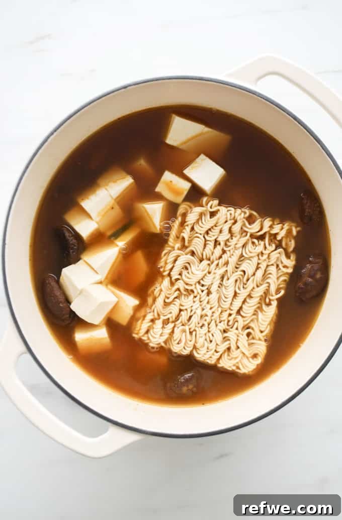 Effortless Vegan Ramen Fix 10 Vegan ramen soup with tofu and ramen noodles added to the broth in a white pot