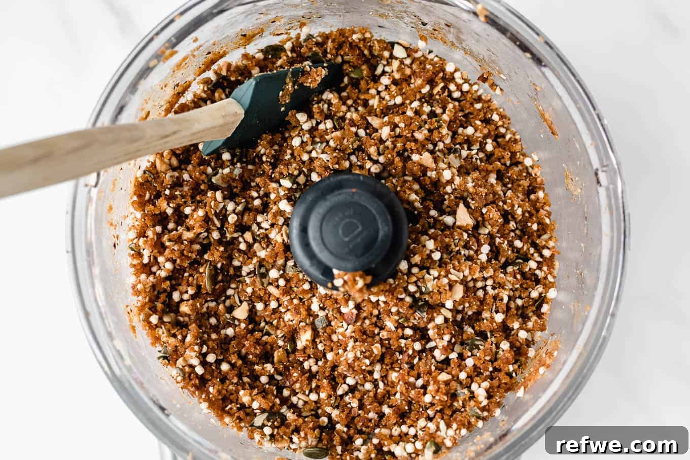 Crispy Quinoa Nut Bars 12 A food processor bowl containing the completed quinoa date and nut bar mixture, showing visible textures.