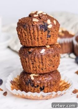 Close-up of a stack of blueberry oat bran muffins, showcasing their crispy tops and plump blueberries