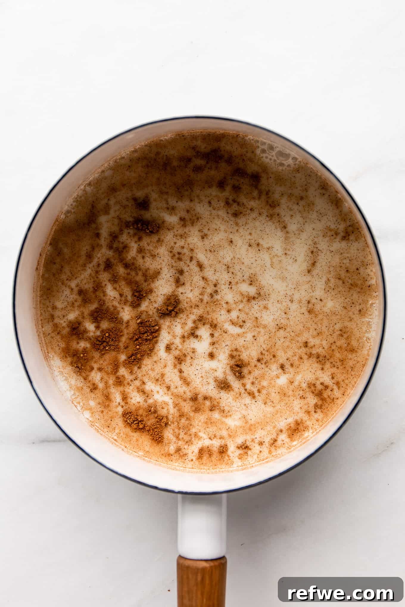 Homebrewed Chai Spice Bliss 5 Oat milk and ground spices being whisked together in a white pot.