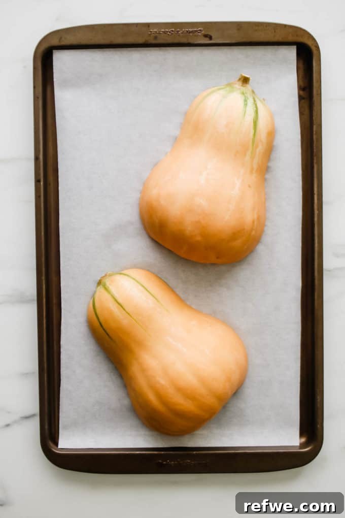 Butternut squash halves placed face down on a baking sheet, ready for roasting.