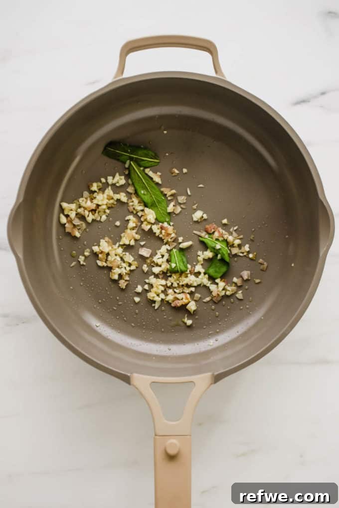 Finely chopped sage, garlic, and shallots sautéing in a pan with olive oil.