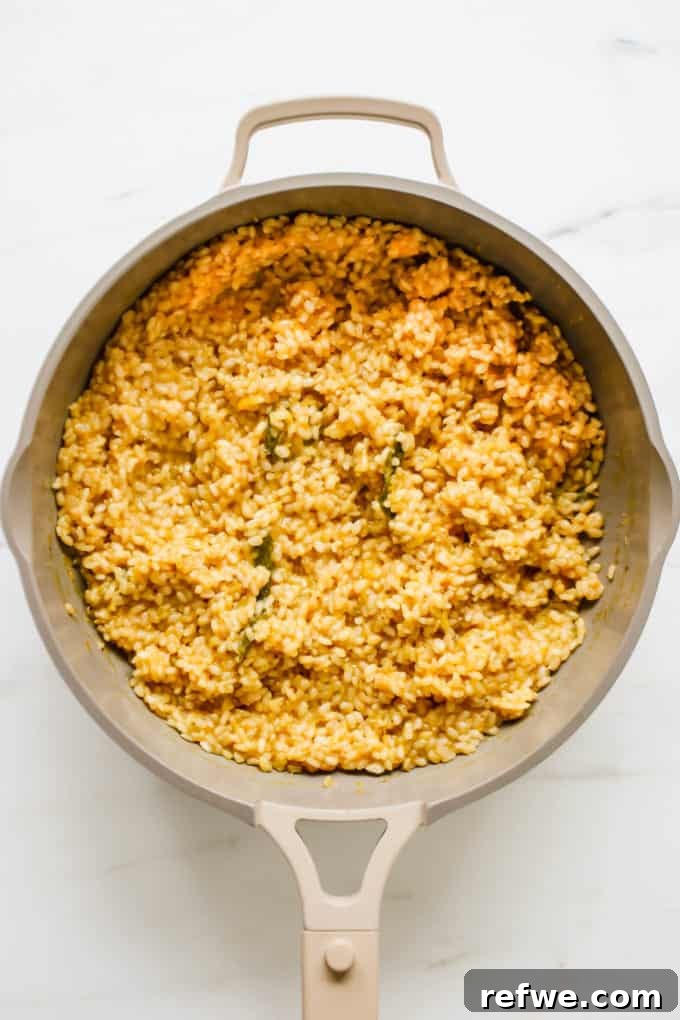 Creamy butternut squash risotto simmering in a pan, almost ready to serve.