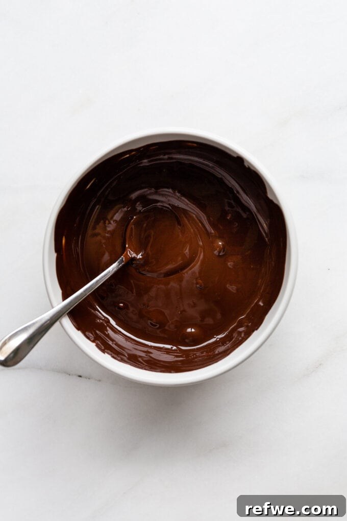 Wintermint Swirl Bark 5 Rich, glossy dark chocolate melted in a bowl, showcasing its smooth texture for peppermint bark.