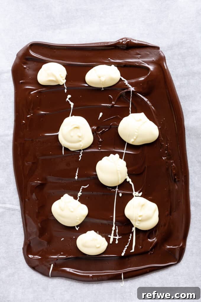 Wintermint Swirl Bark 7 Dark chocolate base with dollops of white chocolate on top, ready to be swirled for the marbled effect in peppermint bark.