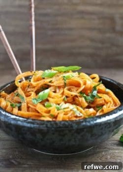 Coconut Curry Linguini in a bowl, with fresh herbs and a lime wedge