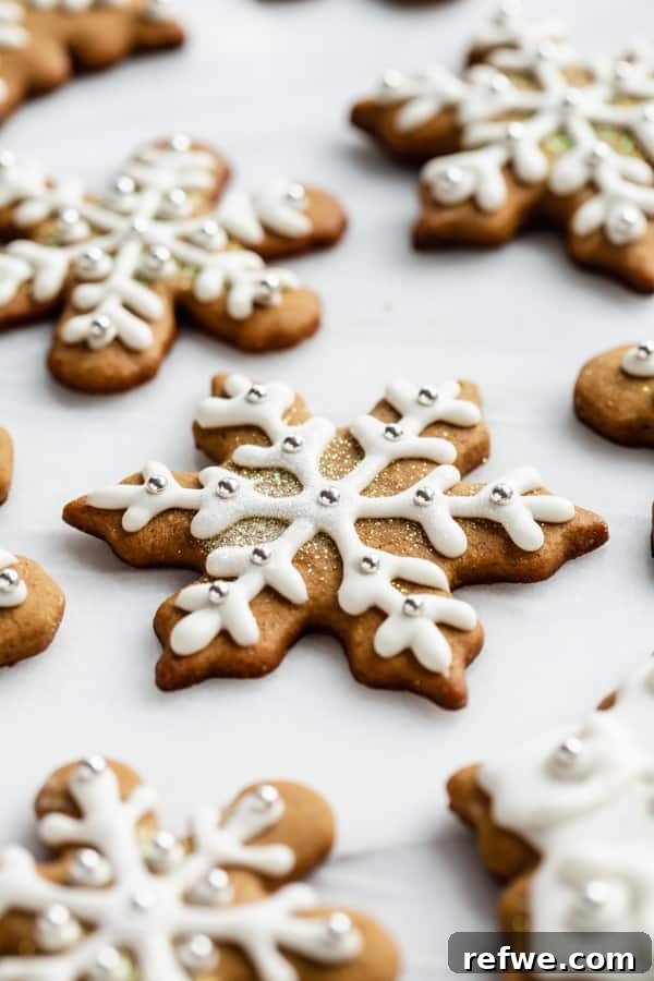 Effortless Wholesome Gingerbread Cookies 3 snowflake gingerbread cookies with royal icing on a marble board