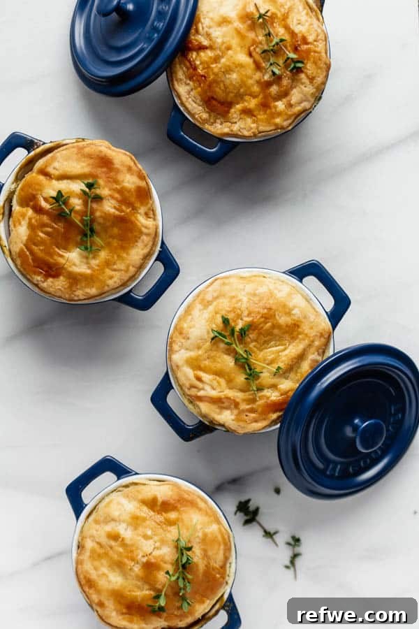 Effortless Garden Pot Pie 3 Four beautifully baked vegetable pot pies with golden puff pastry crusts, presented in small blue ramekins.