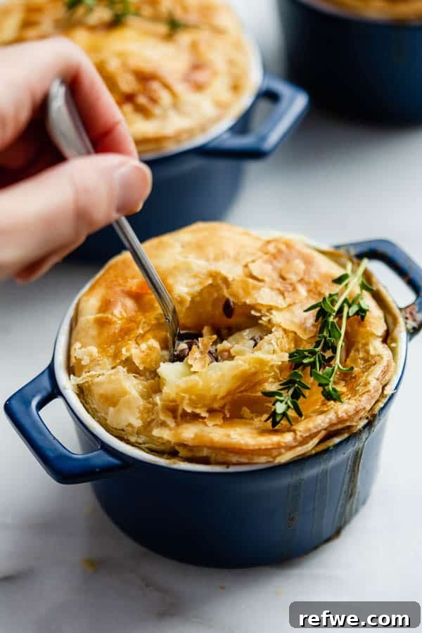 Effortless Garden Pot Pie 5 A spoon scooping a bite of vegetarian pot pie from a blue ramekin, showing the creamy filling and flaky crust.
