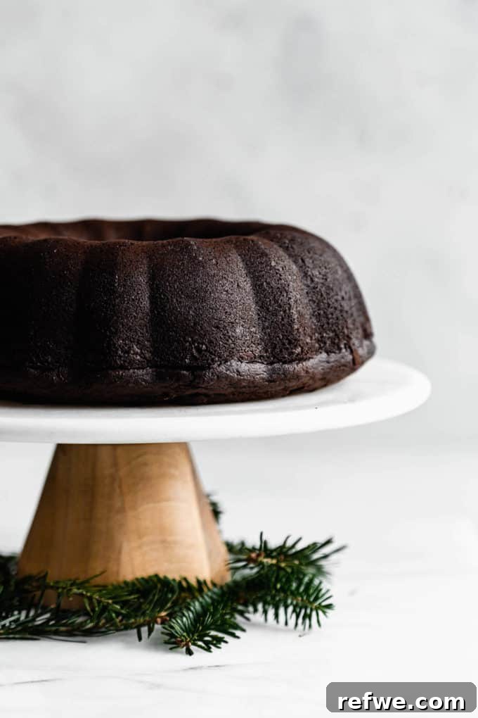 A wooden and marble cake stand with a gingerbread bundt cake on it, ready for glazing and serving.