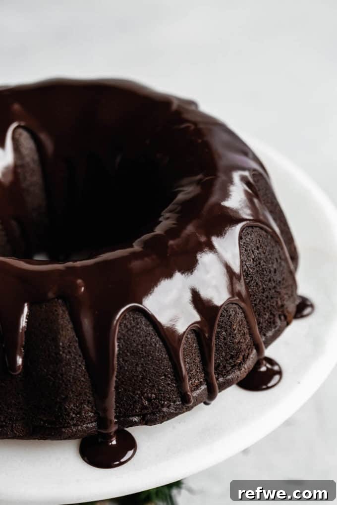 A close up of a gingerbread bundt cake with chocolate glaze dripping down the sides, showcasing the delectable topping and the cake's perfect texture.