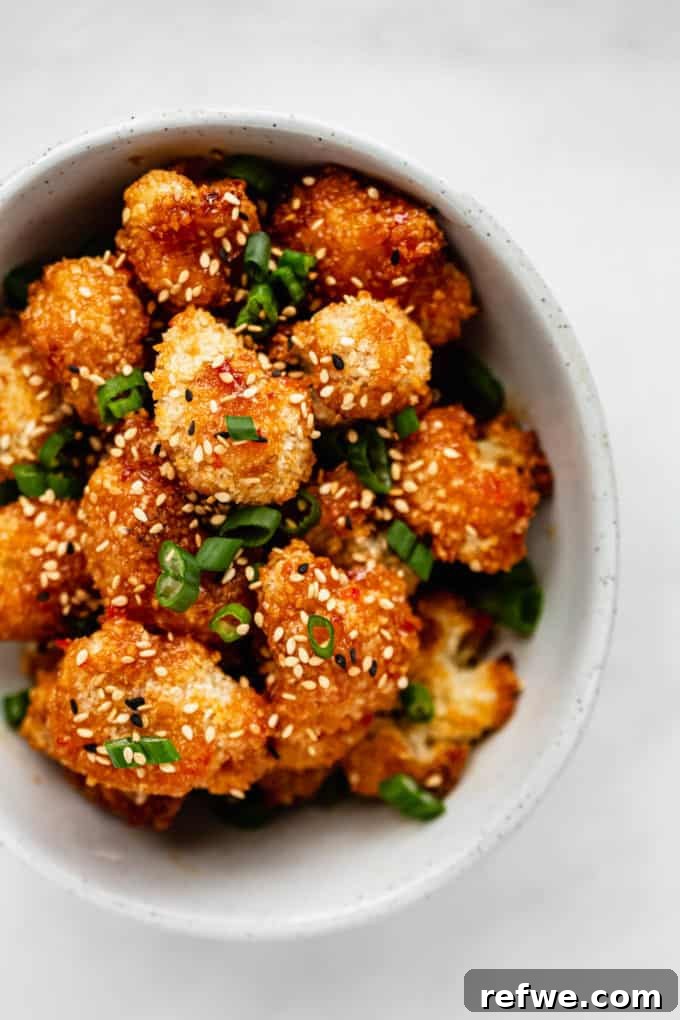 Dynamite Cauliflower 9 A vibrant bowl of panko-crusted cauliflower, topped generously with freshly sliced green onions and sesame seeds