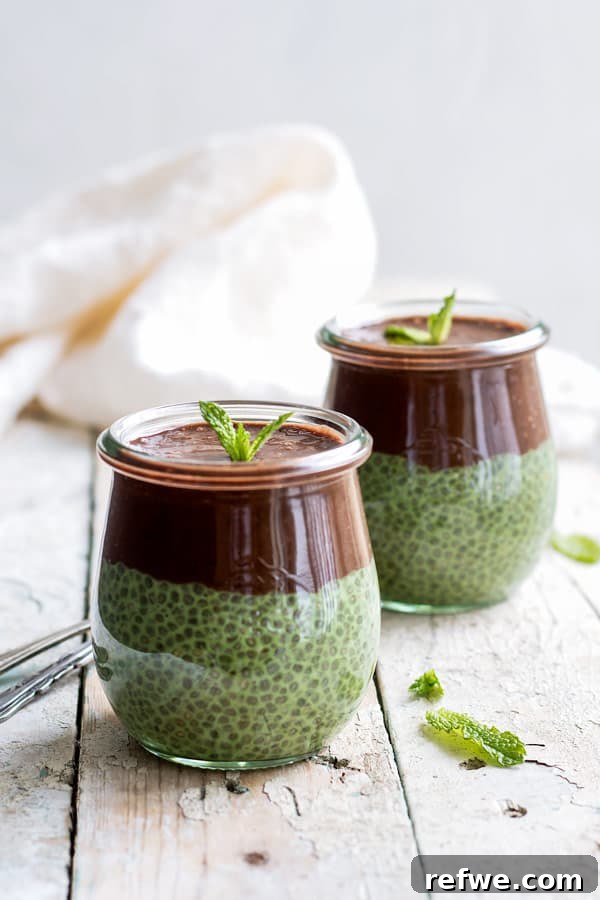 Refreshing Mint Chocolate Matcha Chia Pudding 4 Two jars of green chia pudding topped with a rich chocolate smoothie, garnished with mint, on a white wooden table.