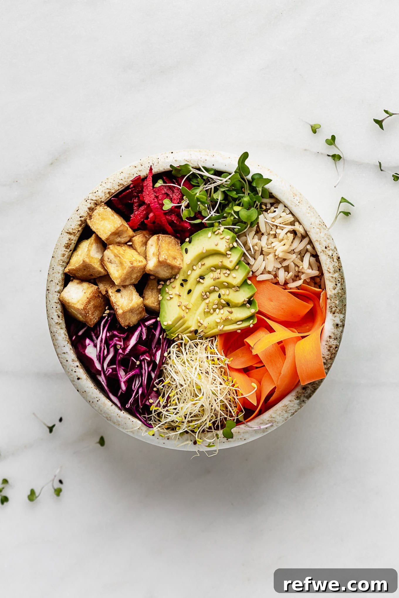 Legendary Dragon Bowls 2 A vibrant tofu power bowl brimming with colorful fresh vegetables, creamy avocado slices, and fluffy brown rice, all drizzled with a rich, savory sauce.