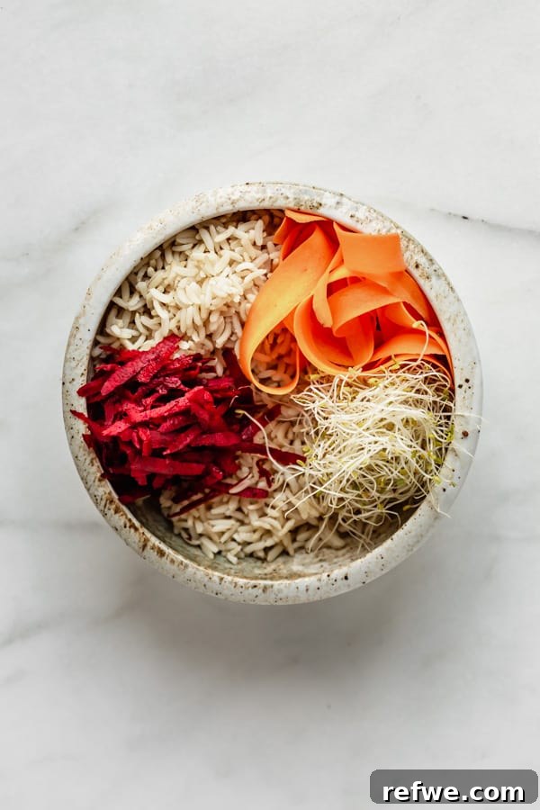 Legendary Dragon Bowls 6 Brown rice, shredded beets, carrots, and delicate alfalfa sprouts arranged neatly in a white ceramic bowl, showcasing fresh ingredients.