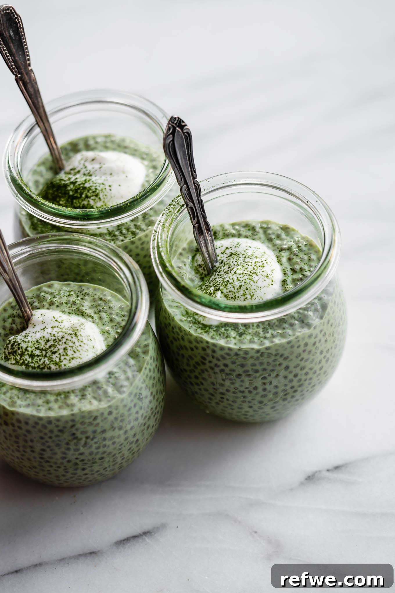 Vibrant Matcha Chia Pudding 2 Three jars of vibrant green matcha chia pudding, topped with creamy yogurt and a dusting of matcha powder, ready to be enjoyed.