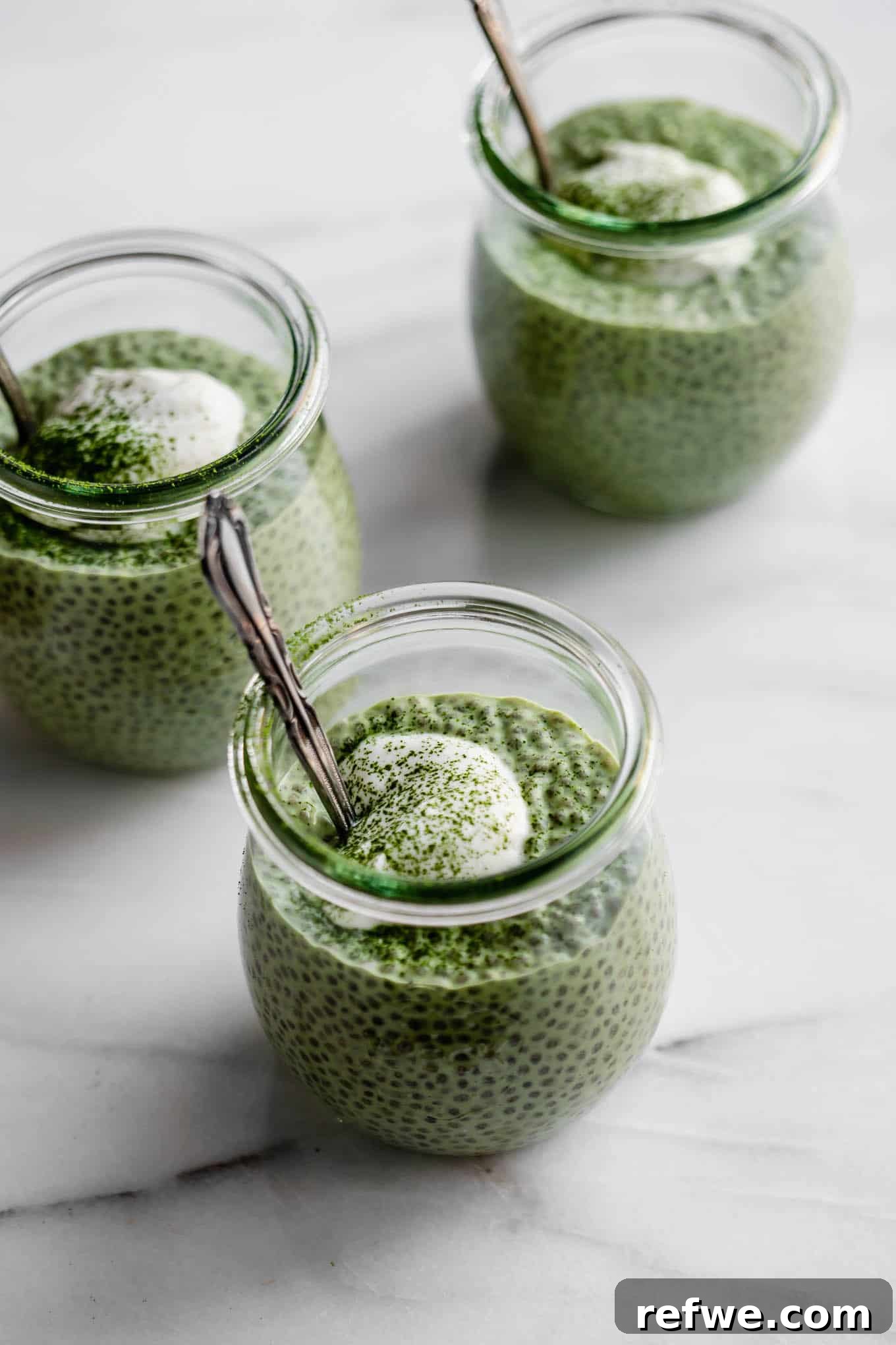 Vibrant Matcha Chia Pudding 8 A top-down view of three small jars filled with vibrant green matcha chia pudding, each with distinct layers and textures.