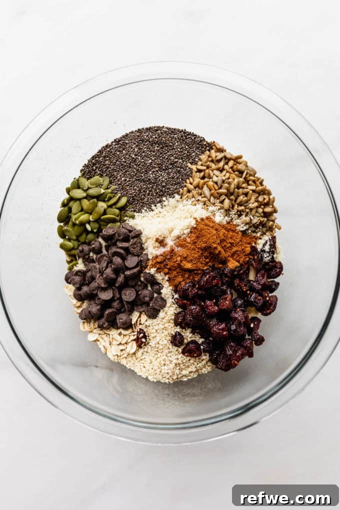 Wholesome Morning Cookie Delights 4 A large mixing bowl filled with a colorful array of dry ingredients including oats, nuts, seeds, dried cranberries, and dark chocolate chips, ready for mixing.