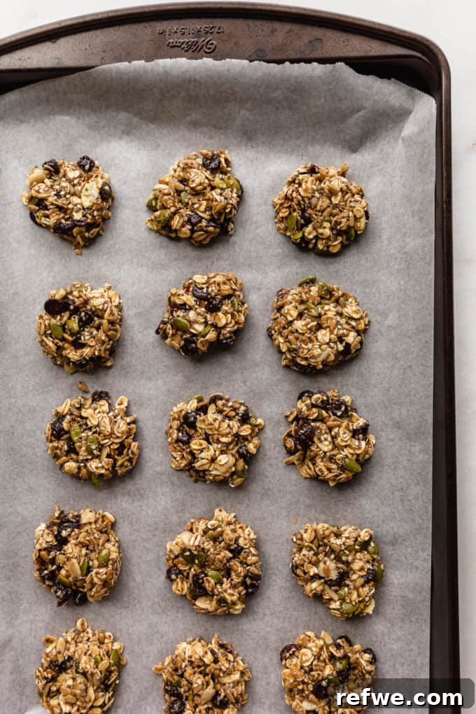 Wholesome Morning Cookie Delights 8 A baking sheet lined with parchment paper, featuring perfectly scooped and flattened unbaked healthy breakfast cookies, ready for the oven.