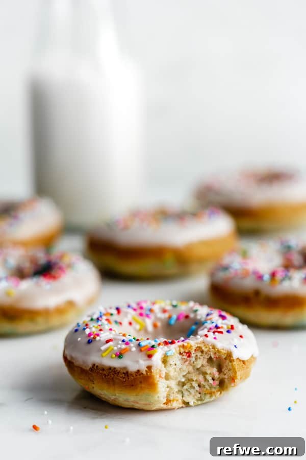 Vegan Cake Batter Bliss Donuts 5 Close-up of a stack of vegan cake batter donuts with generous vanilla icing and sprinkles