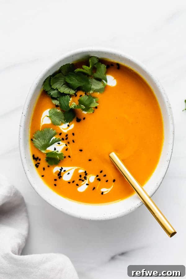 Bowl of Thai carrot ginger soup with fresh herbs and toppings