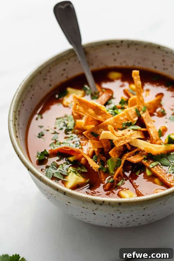 Smoky Plant-Powered Tortilla Soup 7 A beautifully presented bowl of vegan tortilla soup in a ceramic bowl, generously topped with crispy tortilla chips.