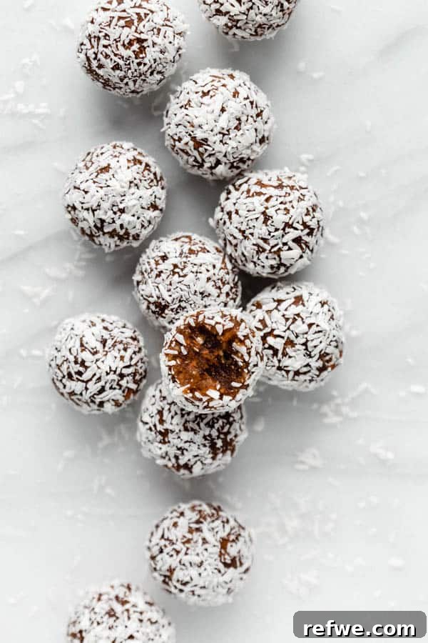 A close-up of a perfectly rolled Carrot Cake Energy Ball coated in shredded coconut.