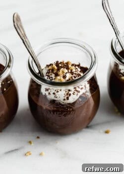 A cup of chocolate chia mousse topped with yogurt, walnuts and chocolate shavings.