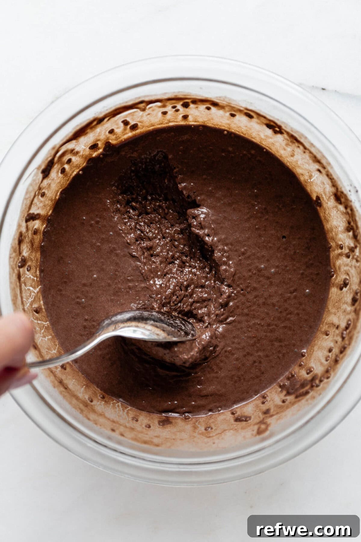 Silky Chocolate Chia Pudding 8 A spoon scooping creamy chocolate chia mousse out of a mixing bowl, showcasing its rich texture before serving.