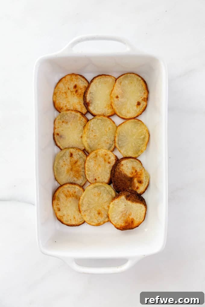 sliced potatoes layered in a baking dish