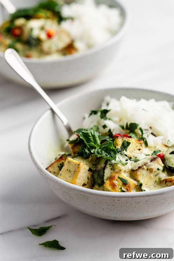 Vibrant Thai Green Tofu Curry 5 A ladle serving creamy Thai green curry tofu into a bowl with jasmine rice, garnished with fresh herbs.