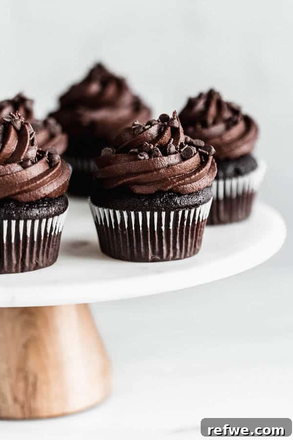 A collection of beautifully decorated vegan chocolate cupcakes with rich chocolate frosting, displayed on an elegant cake stand.