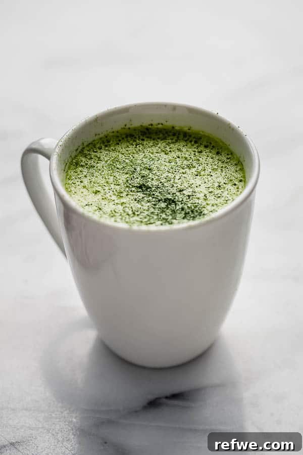 A beautifully presented matcha tea latte in a stylish mug, with subtle background elements.