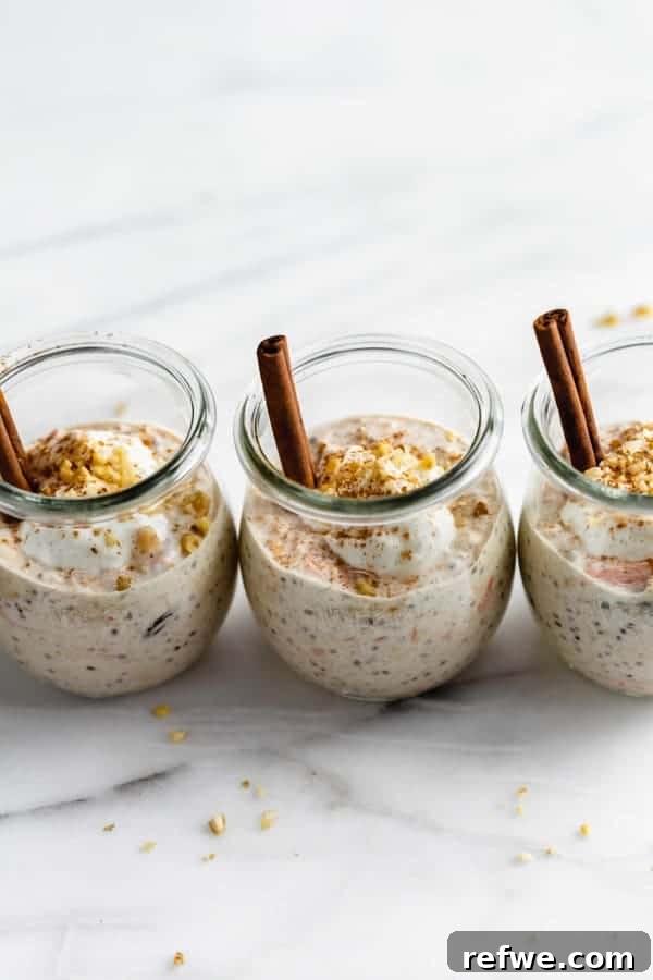 A single jar of carrot cake overnight oats with fresh shredded carrots and a cinnamon stick garnish, presented on a light wooden surface.