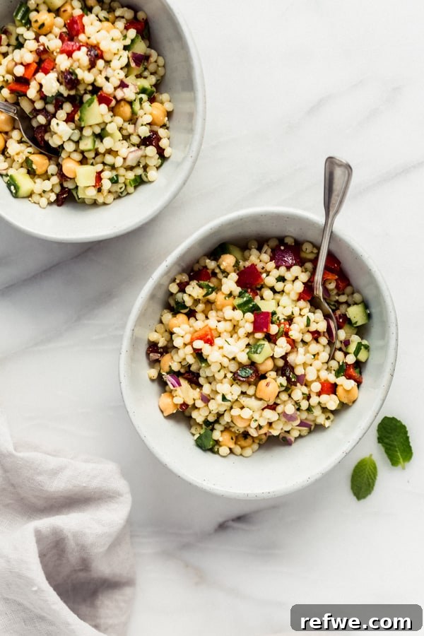 Two bowls of Israeli couscous salad, garnished and ready to be served