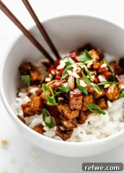 Kung pao tofu on rice in a white bowl, ready to be served.