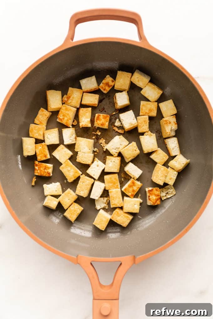Effortless Kung Pao Tofu 4 Pan-fried cubes of golden-brown tofu in a vibrant pink pan, ready for the next step of the Kung Pao Tofu recipe.
