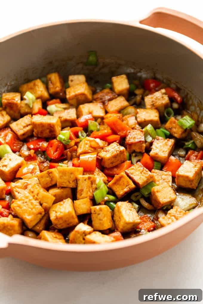 Effortless Kung Pao Tofu 6 The Kung Pao Tofu simmering in a vibrant pink pan, coated evenly with the rich, glossy sauce.
