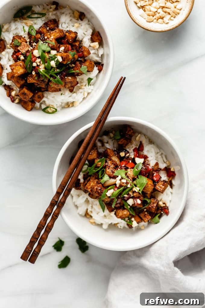Effortless Kung Pao Tofu 7 Two enticing bowls of Kung Pao Tofu served over fluffy white rice, adorned with wooden chopsticks, ready for a delicious meal.