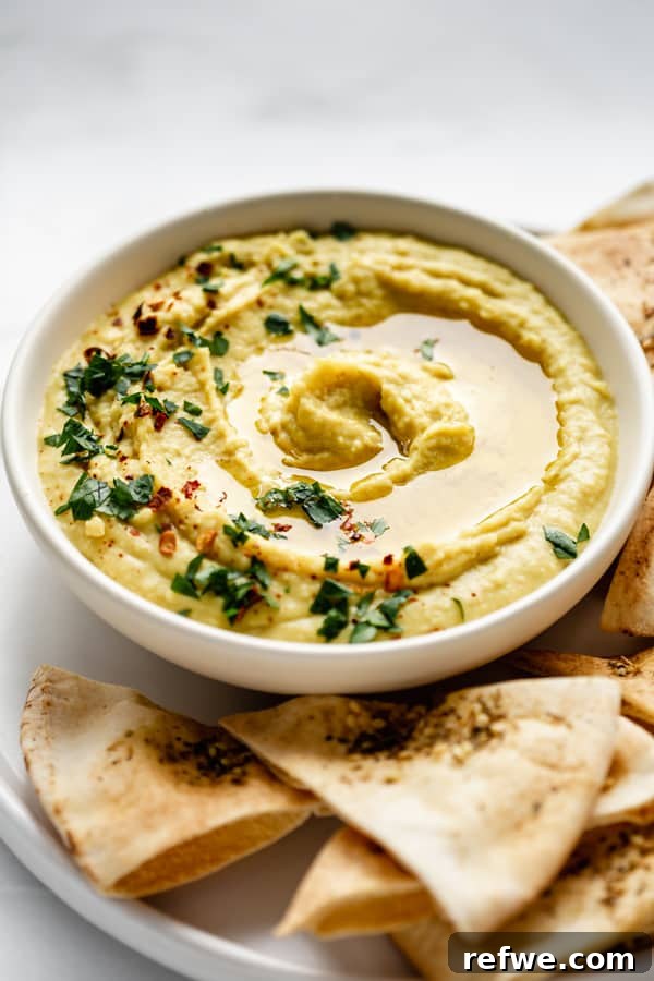Close-up of a creamy curried white bean dip garnished with fresh herbs and a drizzle of olive oil, highlighting its rich texture and appetizing appeal.