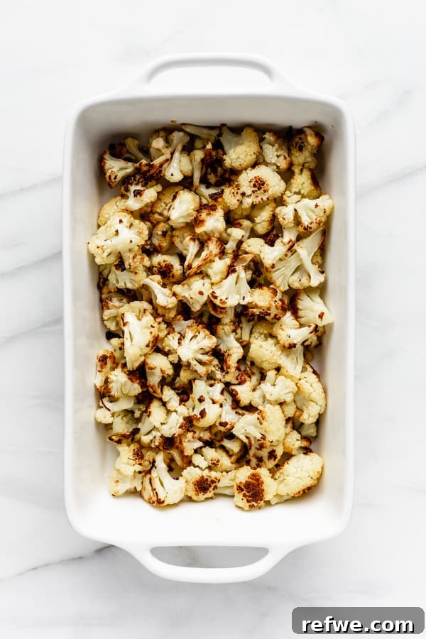Smoky Cauliflower Tinga Tacos 3 Close-up of cauliflower florets roasting in a baking dish, golden brown and perfectly caramelized.