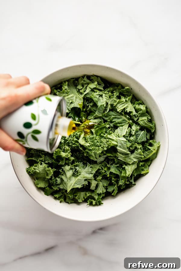 Perfectly Tender Massaged Kale Salad 5 Hands gently massaging kale leaves with olive oil in a bowl, demonstrating the tenderizing process.