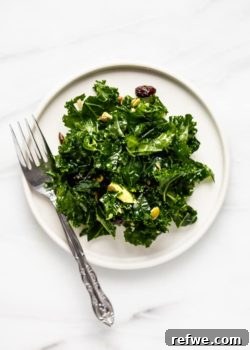 A single plate of a beautifully plated massaged kale salad, showcasing its vibrant colors and inviting textures.