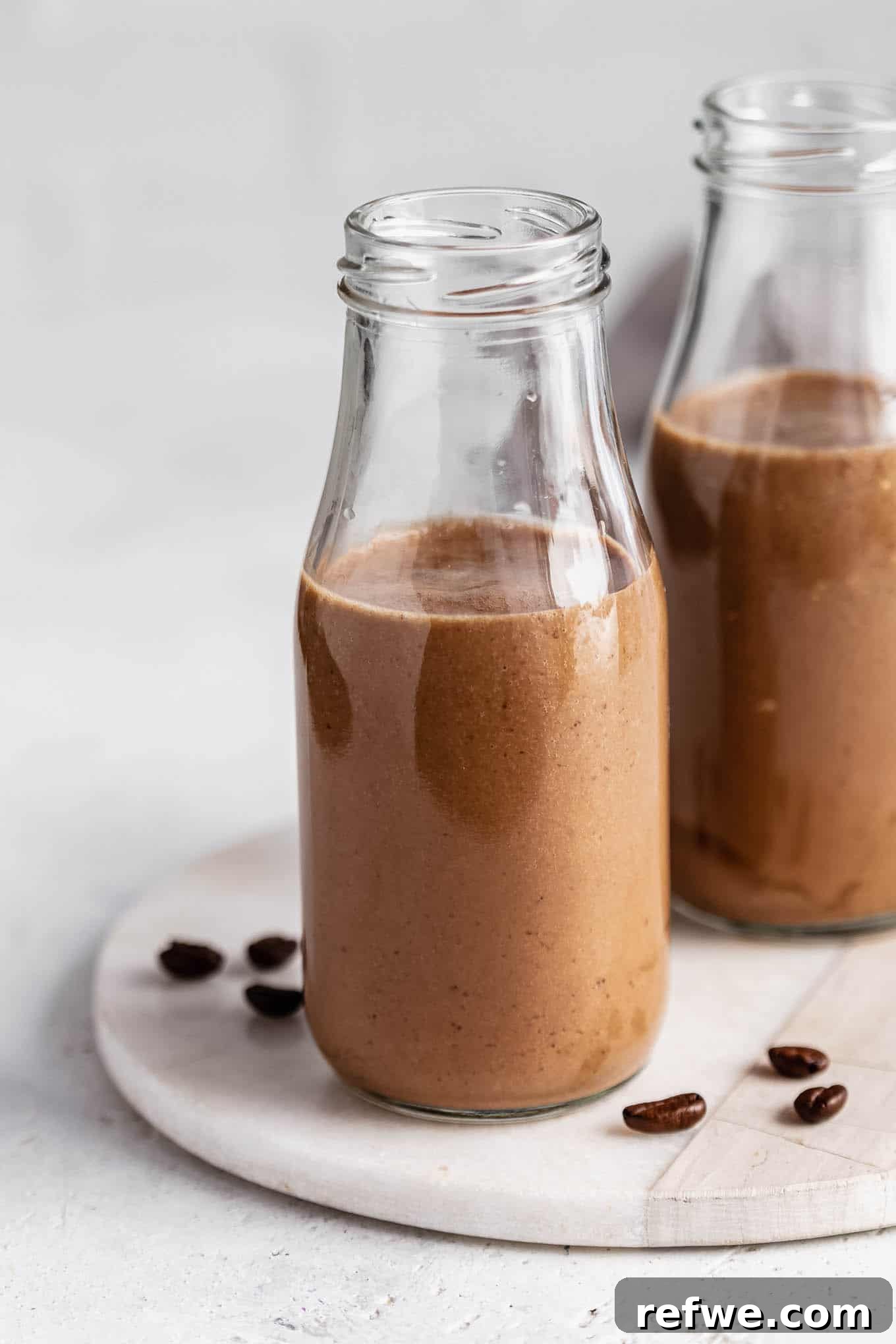 Banana Java Blend 2 Two jars of creamy banana coffee smoothie on a elegant marble tray, garnished with coffee beans