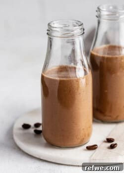 Two jars of creamy banana coffee smoothie on a marble tray, ready to be served