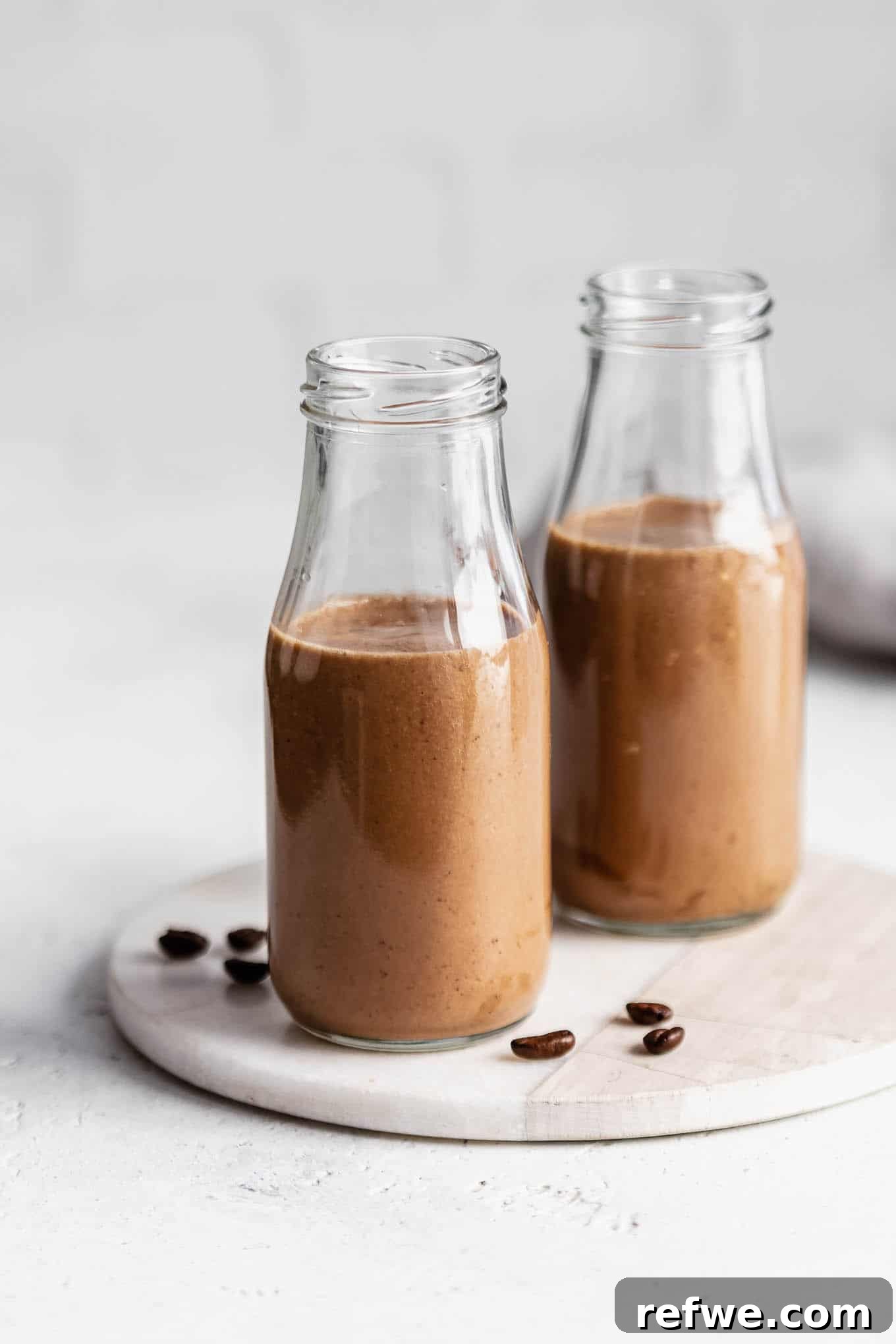 Banana Java Blend 7 Two jars of banana coffee smoothies presented with scattered coffee beans and whole bananas, highlighting the main ingredients.