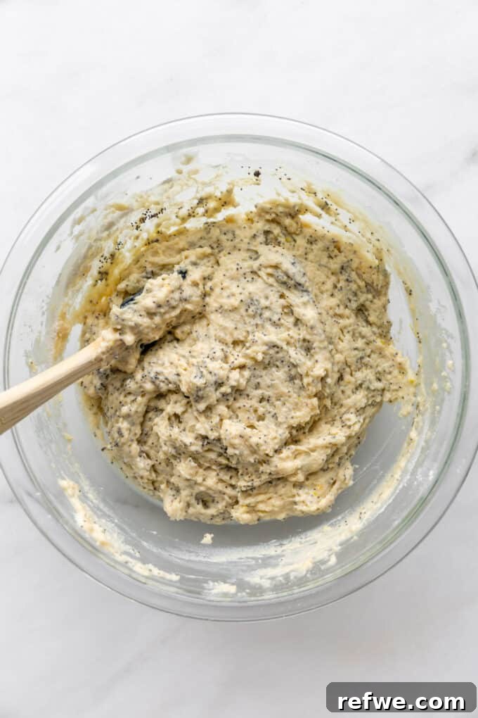 Wholesome Lemon Poppy Seed Delights 8 The lemon poppy seed muffin batter, with poppy seeds evenly distributed, in a mixing bowl.