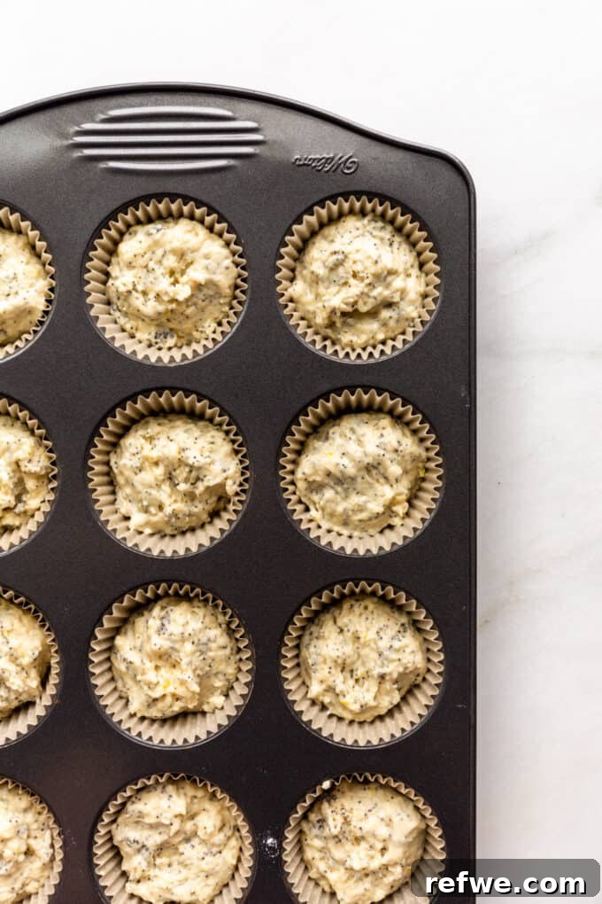 Wholesome Lemon Poppy Seed Delights 9 Unbaked lemon poppy seed muffin batter in a lined muffin pan, ready for the oven.