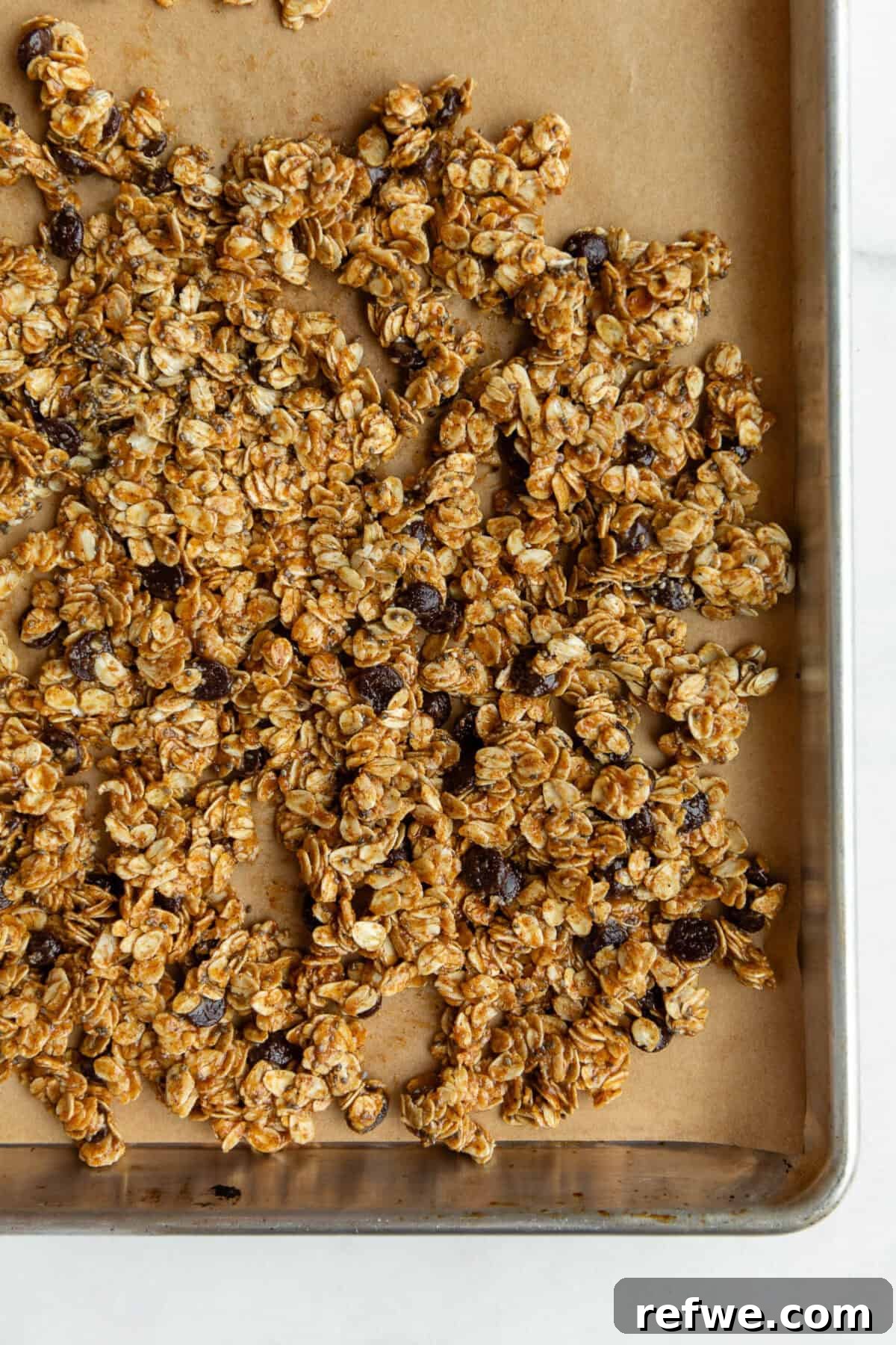 Chocolate Chip Cookie Crunch Granola 8 Unbaked cookie dough granola mixture evenly spread on a baking sheet lined with parchment paper.