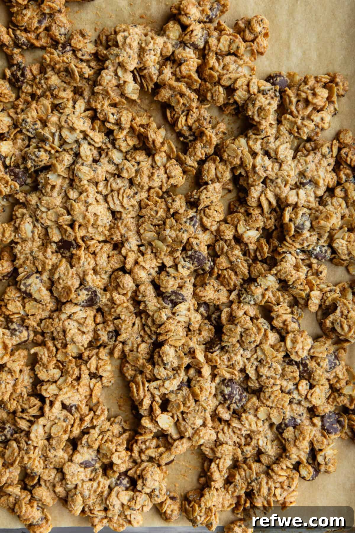 Chocolate Chip Cookie Crunch Granola 9 The chocolate chip cookie dough granola mixture is baking on a pan, forming golden clusters.